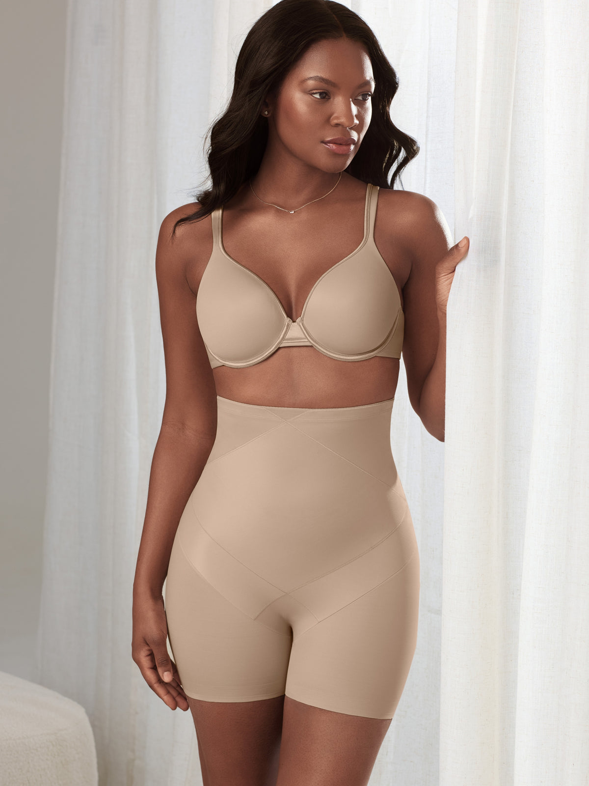 a woman in a living room wearing a nude high waisted tummy control short shapewear all-groups