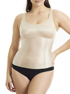 Woman wearing a beige shapewear tank top and black underwear on a white background
