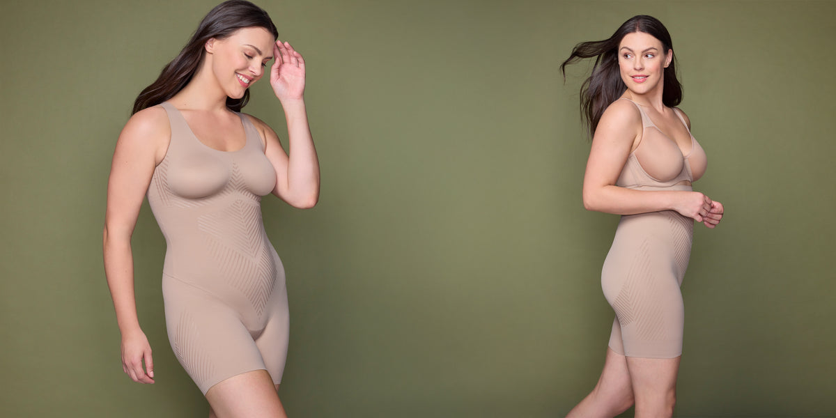 a woman wearing a nude shaping romper bodysuit and a nude high waist thigh slimmer against an olive colored wall
